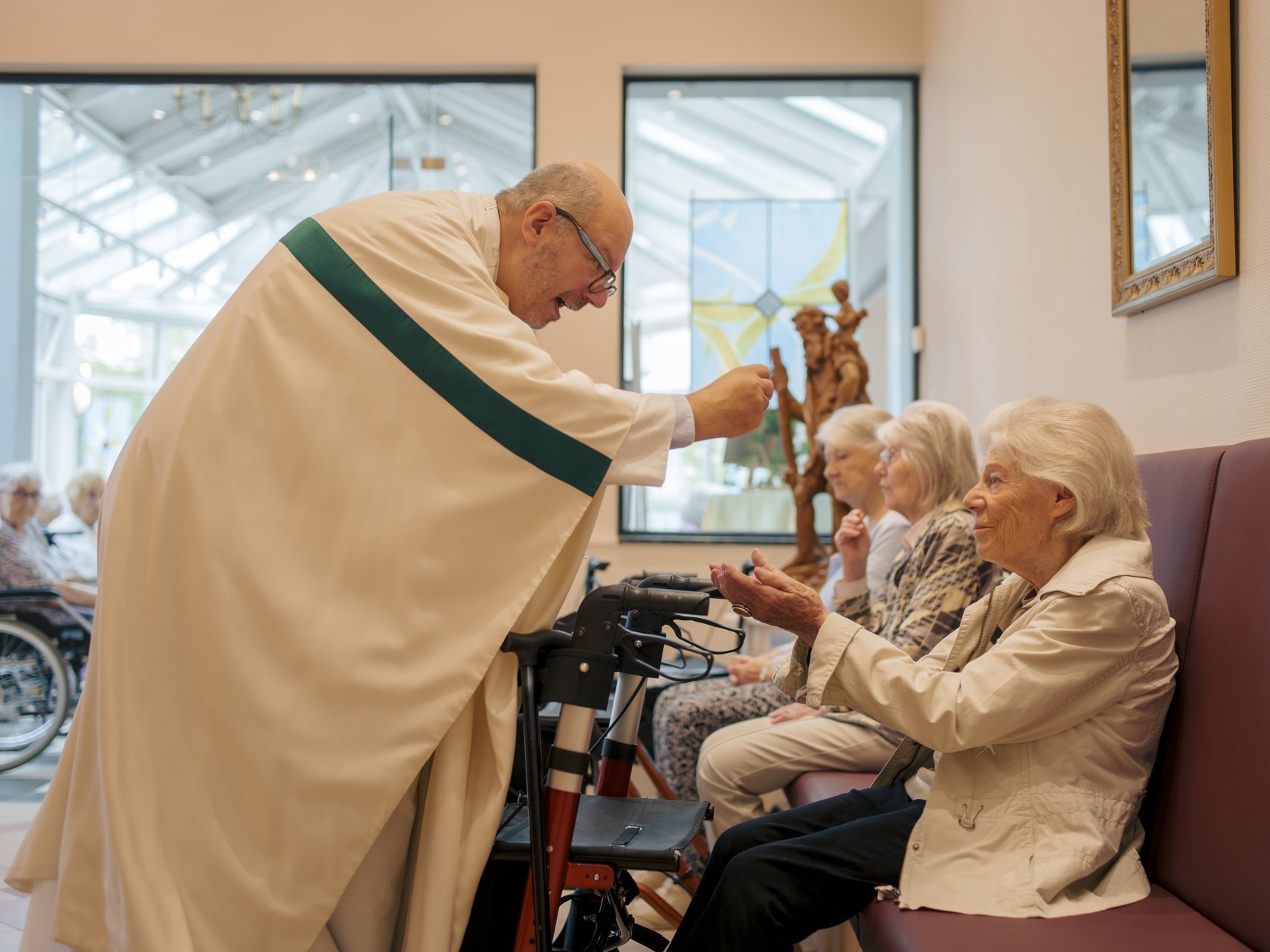 Ein Pfarrer gibt einer Frau ein Leib Christi in die Hand 