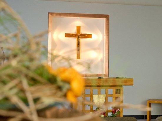 Ein Altar mit dem Jesuskreuz als zentralem Element, stimmungsvoll beleuchtet.