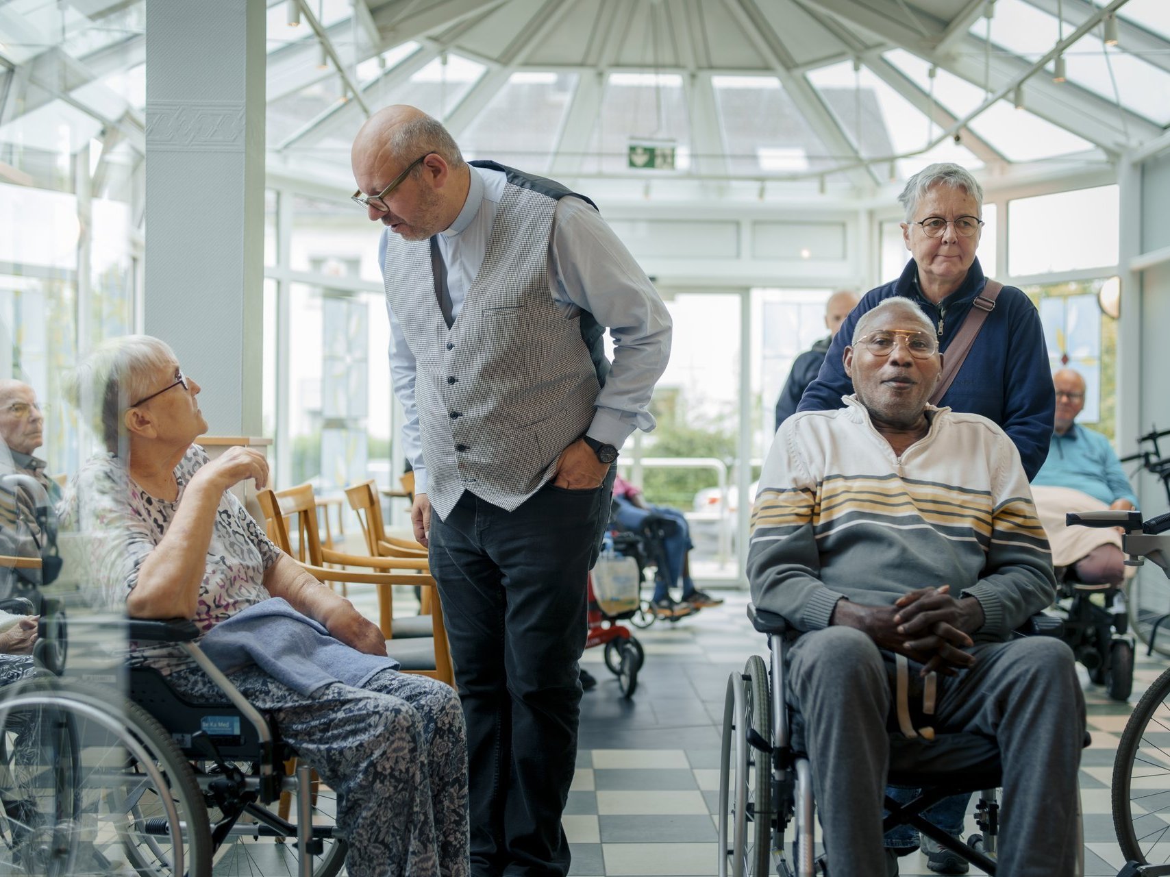 viele Personen stehen oder sitzen in einem Raum und unterhalten sich 